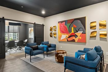 A living room with a blue couch and a painting on the wall.